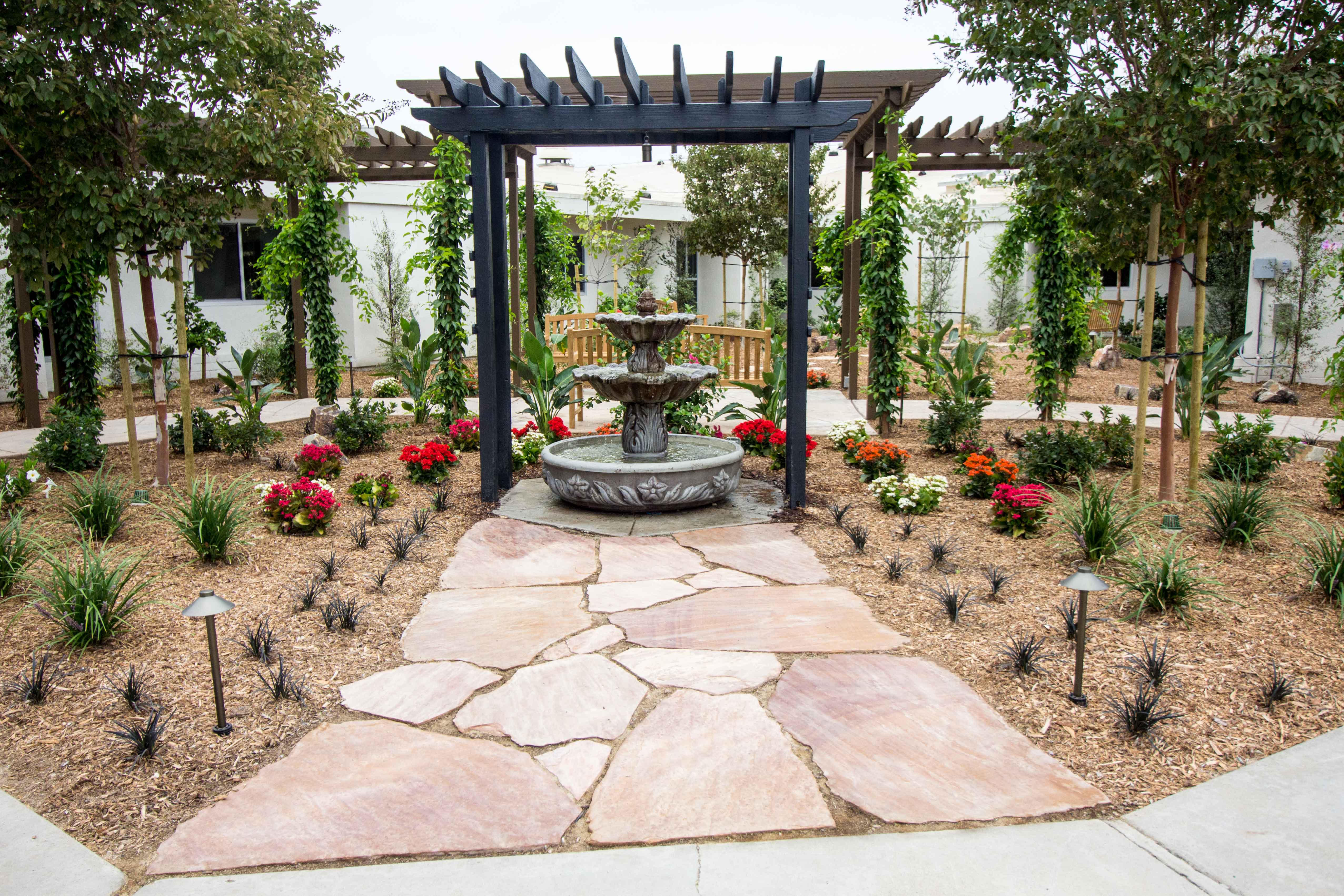 outdoor garden with water fountain underneath pergola